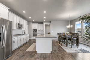 Kitchen featuring decorative backsplash, stainless steel appliances, recessed lighting, and a center island with sink
