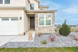 View of exterior entry featuring stone siding and an attached garage