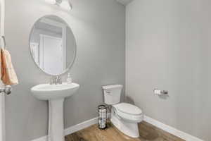 Bathroom with wood finished floors, toilet, baseboards, and a sink