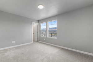 Empty room featuring visible vents, baseboards, a textured ceiling, and light colored carpet