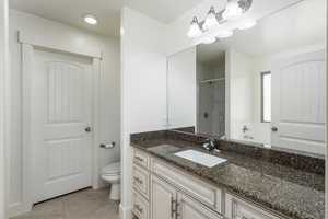 Full bathroom featuring a shower stall, toilet, tile patterned flooring, and vanity