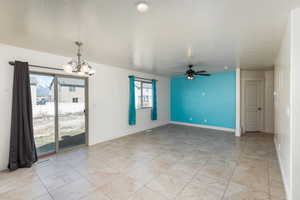 Unfurnished room featuring baseboards, visible vents, and ceiling fan with notable chandelier