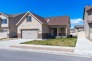 View of front of house with driveway, stone siding, a shingled roof, a front yard, and stucco siding