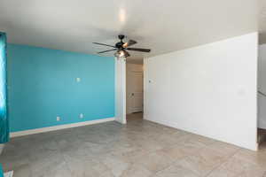 Unfurnished room with a textured ceiling, a ceiling fan, and baseboards