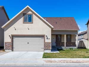 View of front of house with covered porch, stucco siding, concrete driveway, and stone siding