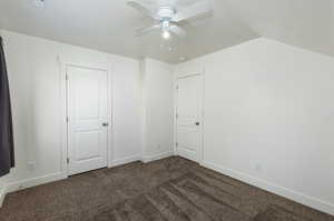 Unfurnished bedroom with a textured ceiling, vaulted ceiling, carpet, and baseboards