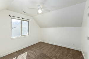 Bonus room with vaulted ceiling, ceiling fan, baseboards, visible vents, and dark carpet
