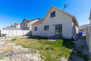 Rear view of property with a yard, entry steps, and fence