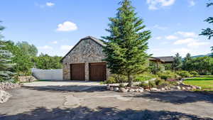 View of front of home with stone siding, concrete driveway, and a garage