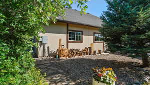 View of side of property featuring stucco siding and roof with shingles