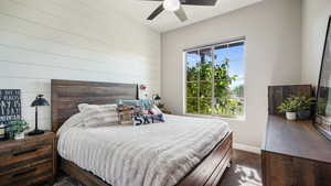 Bedroom featuring dark carpet, wooden walls, and a ceiling fan