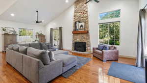 Living room featuring a ceiling fan, high vaulted ceiling, a wood stove, light wood-type flooring, and recessed lighting