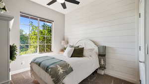 Carpeted bedroom with wooden walls and a ceiling fan