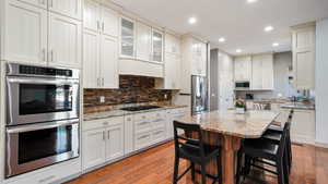 Kitchen featuring stainless steel appliances, a breakfast bar area, light wood-style floors, tasteful backsplash, and a center island