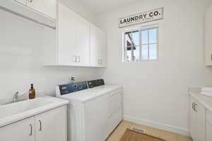 Laundry area featuring cabinet space, washer and clothes dryer, and light tile patterned floors