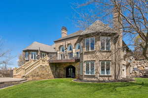View of front facade featuring a chimney, stairway, a deck, a front yard, and stucco siding