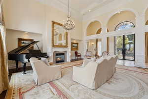 Living room with a notable chandelier, a high ceiling, crown molding, and a glass covered fireplace