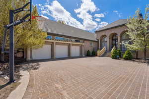 Mediterranean / spanish-style home featuring stucco siding, decorative driveway, a tiled roof, and a garage