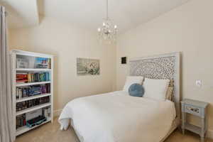 Bedroom featuring an inviting chandelier, carpet flooring, and baseboards