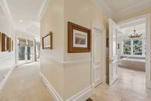 Hall featuring a healthy amount of sunlight, crown molding, and an inviting chandelier
