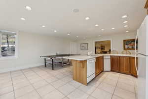 Kitchen featuring light countertops, a sink, white appliances, and recessed lighting