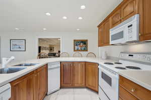 Kitchen featuring brown cabinets, recessed lighting, white appliances, and light countertops
