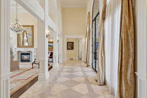Hall with an inviting chandelier, crown molding, and a towering ceiling