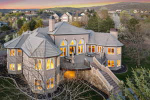 Back of property at dusk featuring a chimney, a mountain view, stairs, and stucco siding