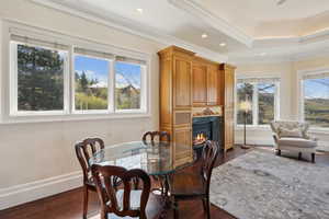 Dining space featuring dark wood finished floors, baseboards, crown molding, and a large fireplace