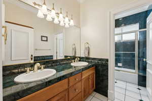 Bathroom featuring double vanity, tile patterned flooring, enclosed tub / shower combo, and a sink