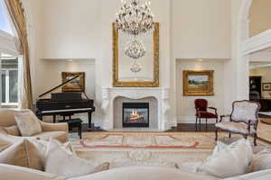 Sitting room with a high ceiling, wood finished floors, a fireplace, baseboards, and a chandelier