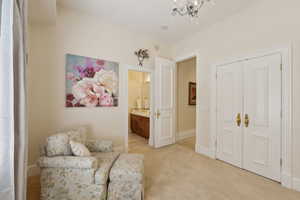 Sitting room with baseboards, an inviting chandelier, and light colored carpet
