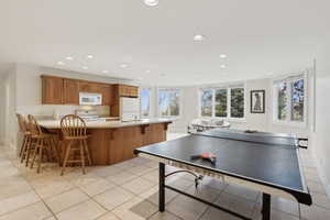 Recreation room with baseboards, light tile patterned flooring, a sink, and recessed lighting