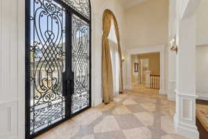 Foyer entrance with crown molding, french doors, and a towering ceiling