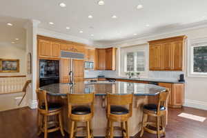 Kitchen featuring paneled refrigerator, a healthy amount of sunlight, a sink, and a kitchen island with sink