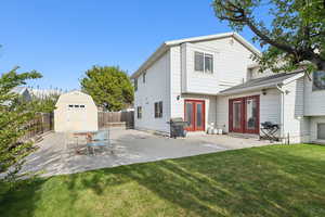 Back of house featuring a patio, french doors, a fenced backyard, and a storage shed