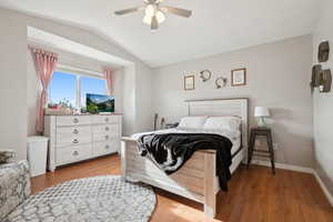 Bedroom featuring lofted ceiling, wood finished floors, a ceiling fan, and baseboards