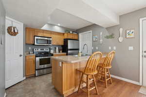 Kitchen featuring a kitchen bar, stainless steel appliances, light countertops, and a sink