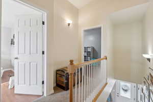 Corridor featuring baseboards, wood finished floors, and an upstairs landing