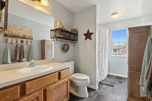 Bathroom featuring baseboards, toilet, a shower with curtain, and vanity