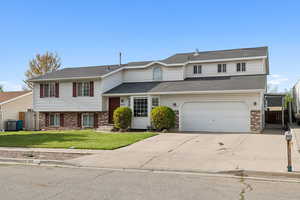 View of front of home featuring a front yard, brick siding, concrete driveway, an attached garage, and fence