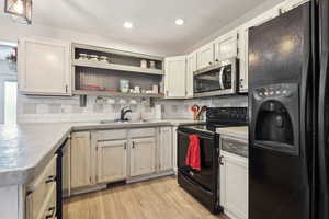Kitchen featuring black appliances, decorative backsplash, light countertops, and a sink