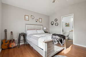 Bedroom with ceiling fan, wood finished floors, ensuite bath, baseboards, and lofted ceiling