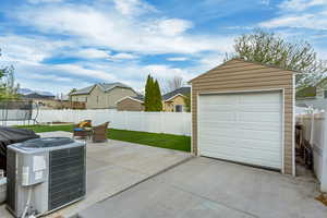 Detached garage with fence, a residential view, cooling unit, driveway, and a trampoline