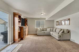 Living room with wooden walls, baseboards, visible vents, and light colored carpet