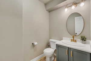 Half bathroom with baseboards, vanity, and toilet