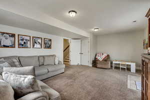 Carpeted living area with stairway, baseboards, and visible vents