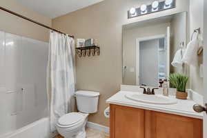 Bathroom featuring shower / bath combination with curtain, toilet, vanity, and tile patterned floors