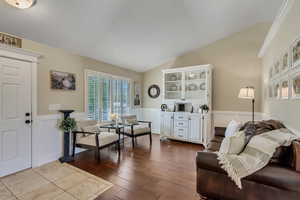Living room with lofted ceiling, a wainscoted wall, and wood finished floors