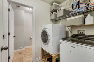 Clothes washing area featuring washing machine and clothes dryer, baseboards, and laundry area
